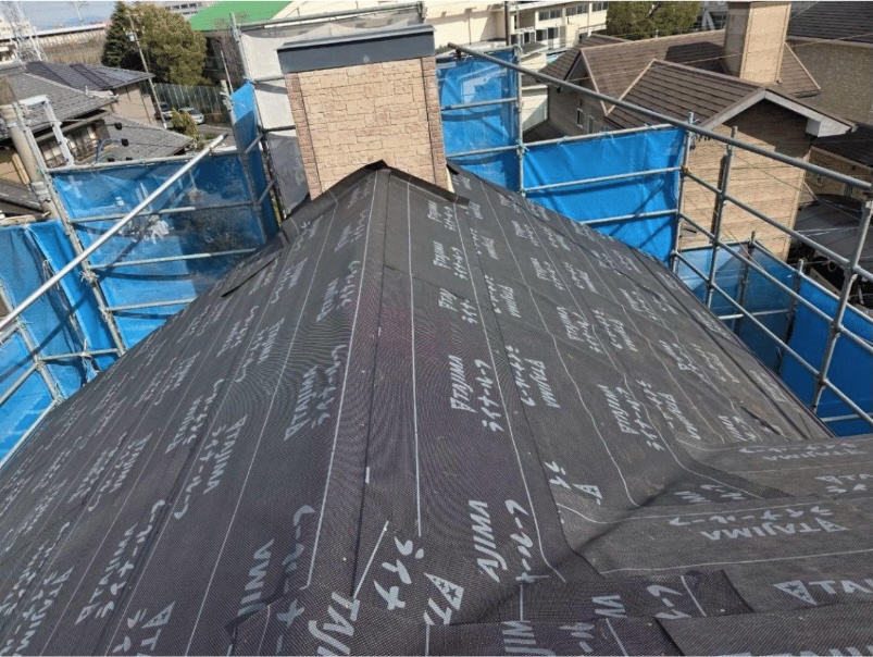 既存の屋根の上から新しい防水紙（ルーフィング）を敷き詰める作業