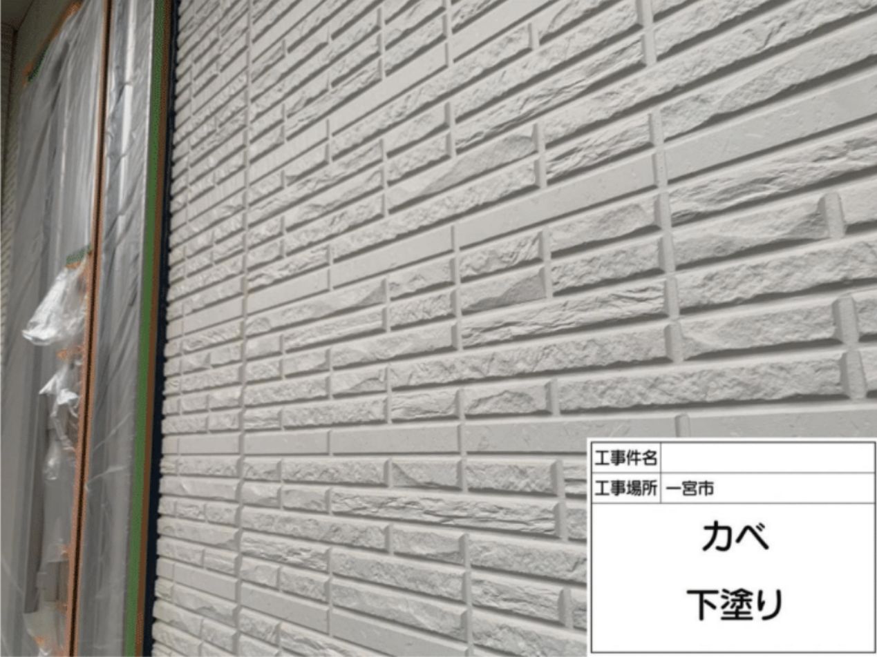 外壁全体に仕上げ塗料の密着性を高めるための下塗り材をローラーで均一に塗る様子
