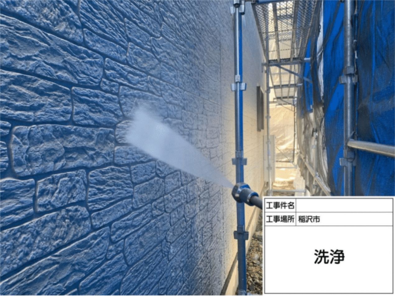 強力な高圧洗浄機を使い、外壁に付着したコケやチョーキングの粉を綺麗に洗い流す様子
