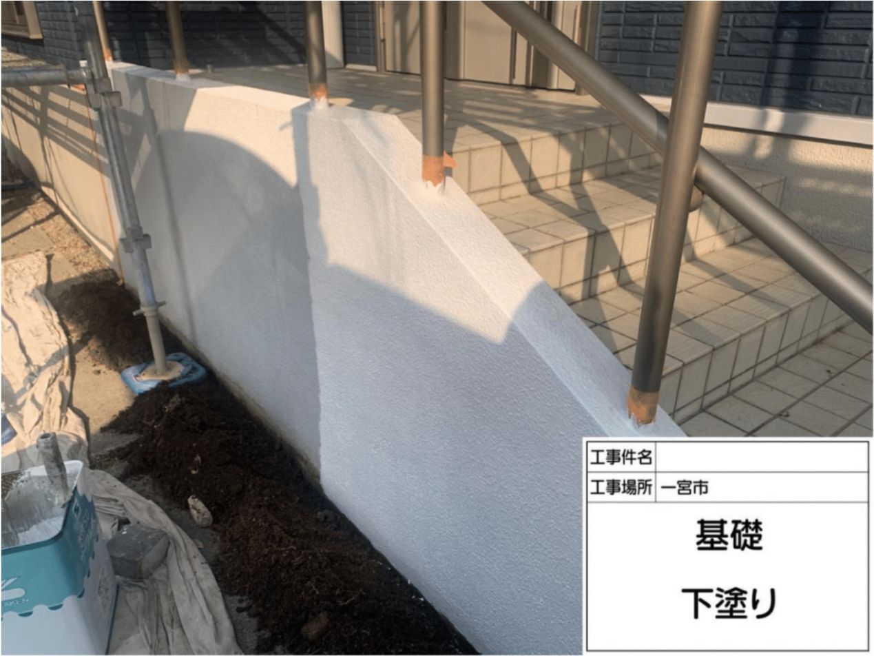 住宅の基礎コンクリート部分に、密着性を高め吸い込みを抑える下塗り材を塗布する様子