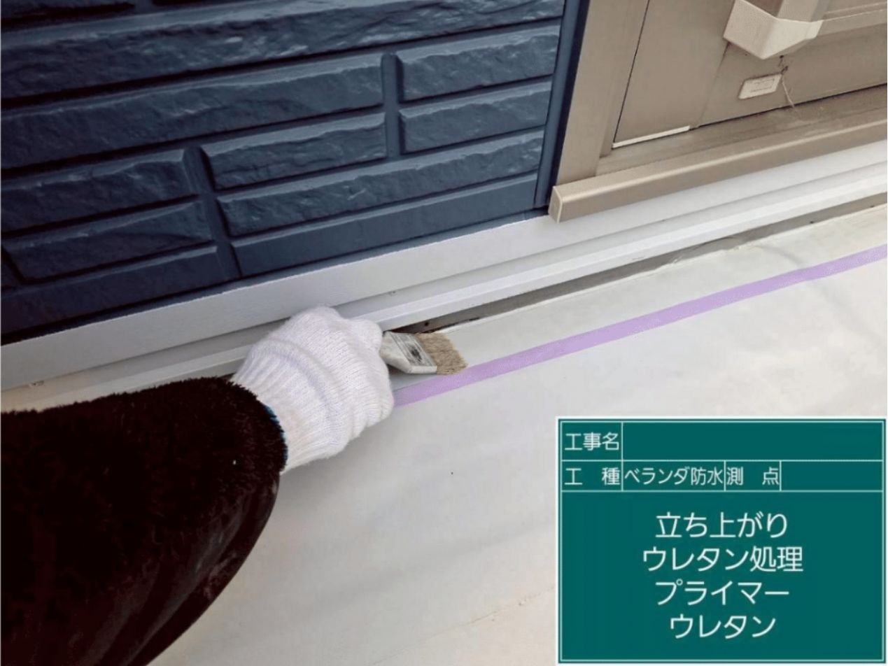 ベランダの壁との立ち上がり部分にプライマーを塗り、防水ウレタン材をハケで丁寧に塗布する様子