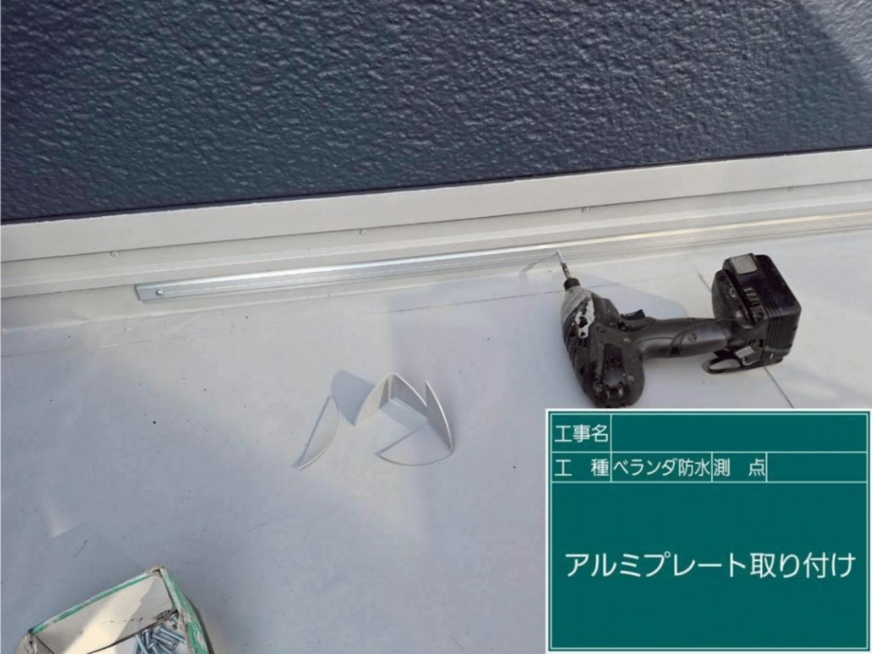 防水シートの端部が浮いてこないよう、アルミプレートをビスで等間隔にガッチリと固定する様子