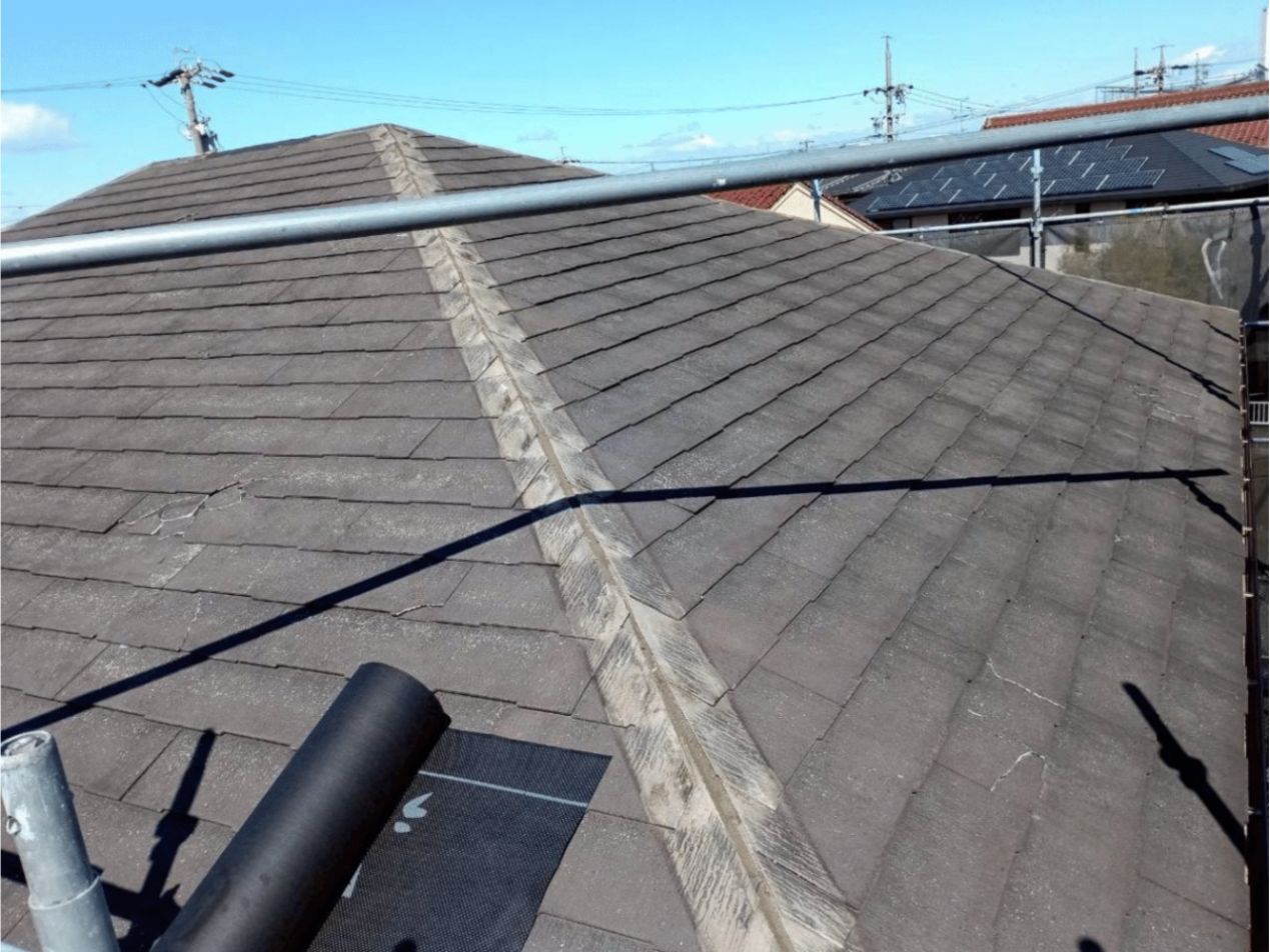 新しい屋根材を平らに重ねるため、古い屋根のてっぺんにある棟板金を丁寧に撤去する様子